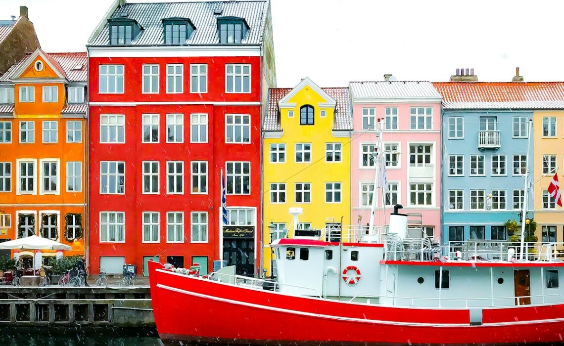 assorted-color buildings near red boat docked on port during daytime